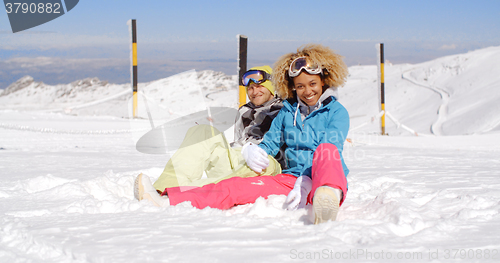 Image of Couple sitting in snow on ski slope