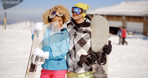 Image of Affectionate young couple posing with snowboards