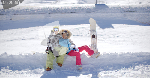 Image of Happy young couple sitting on a deep shelf of snow