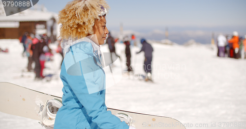 Image of Trendy young woman carrying her snowboard