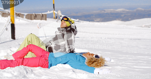 Image of Couple resting on hill after skiing
