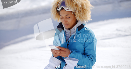 Image of Woman in snowsuit checking phone