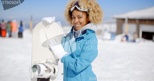 Image of Happy friendly young woman posing with a snowboard