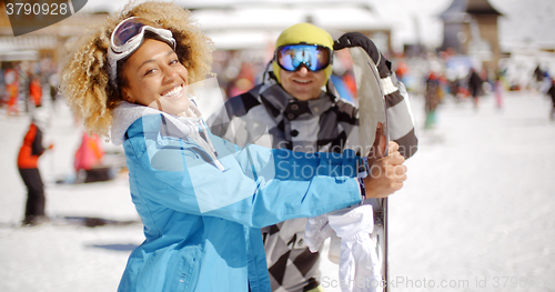 Image of Man flirting with woman holding snowboard