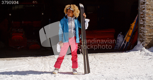 Image of Confident young woman in snowsuit with skis