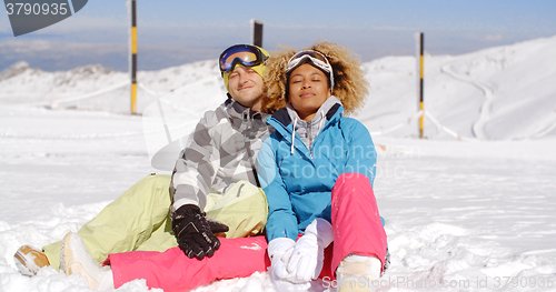 Image of Couple sitting in snow on ski slope