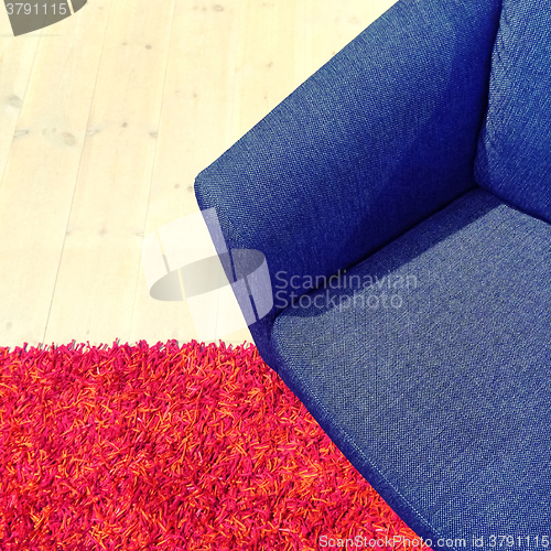 Image of Blue textile armchair on red carpet