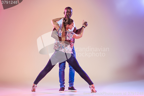 Image of Young couple dances social Caribbean Salsa, studio shot 