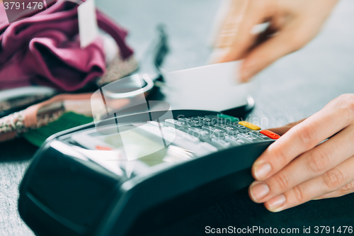 Image of hand swiping credit card in store