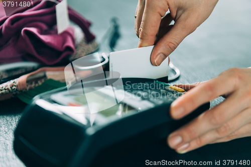 Image of hand swiping credit card in store