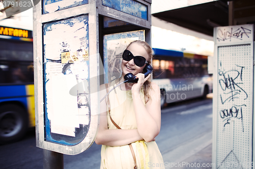 Image of Woman chatting on a public telephone