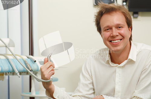 Image of Laughing man with tousled hair holding dental tool