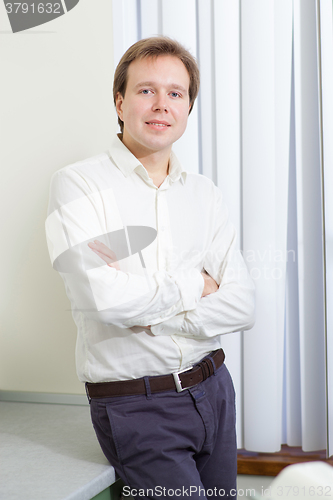 Image of Young man with confident smile and arms folded