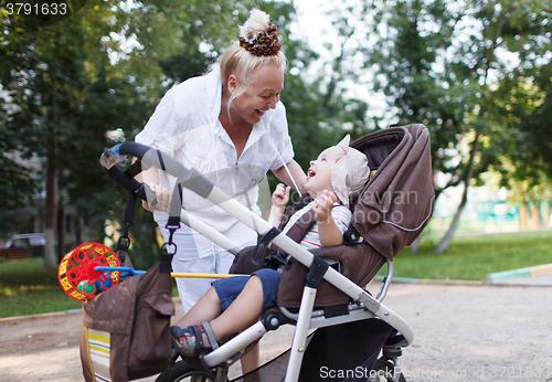 Image of Granny playing with her grandson in pram