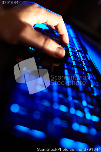 Image of Man\'s hand typing on a blue keyboard.