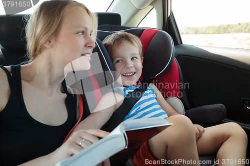 Image of Mother reading a book to son in the car