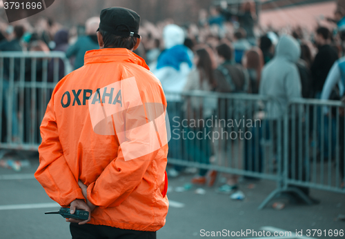 Image of Back security guard in front of blurred crowd