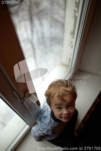 Image of Smiling boy sitting on the windowsill.