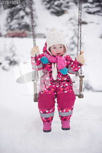 Image of little girl at snowy winter day swing in park