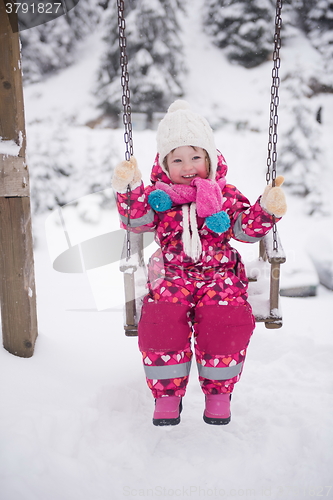 Image of little girl at snowy winter day swing in park