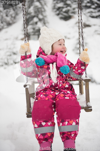 Image of little girl at snowy winter day swing in park