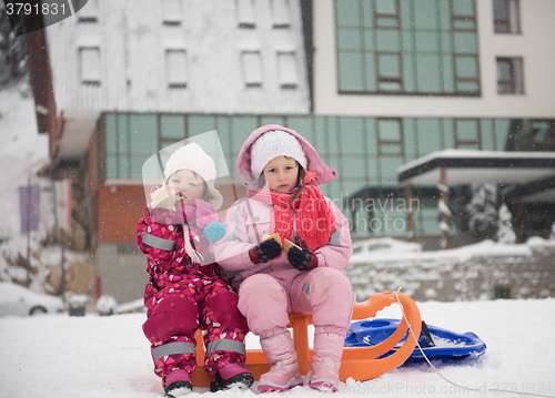 Image of portrait of two little girls sitting together on sledges
