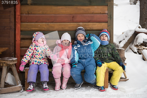 Image of little children group sitting  together  in front of wooden cabi