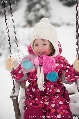 Image of little girl at snowy winter day swing in park