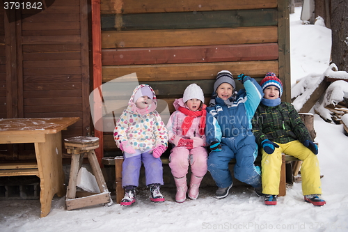 Image of little children group sitting  together  in front of wooden cabi