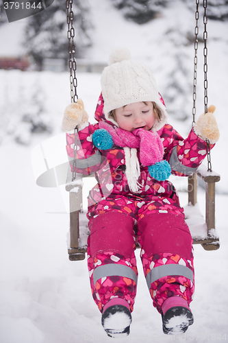 Image of little girl at snowy winter day swing in park