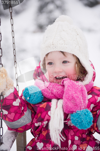 Image of little girl at snowy winter day swing in park