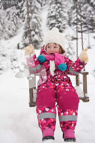 Image of little girl at snowy winter day swing in park