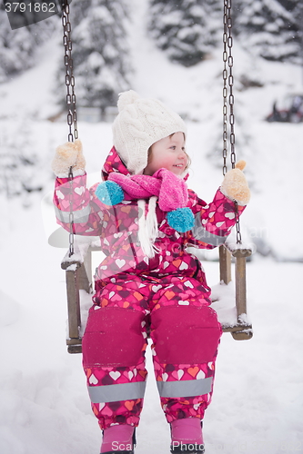 Image of little girl at snowy winter day swing in park