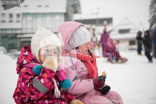 Image of portrait of two little girls sitting together on sledges