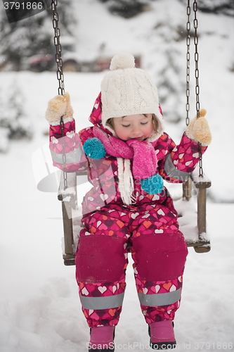 Image of little girl at snowy winter day swing in park