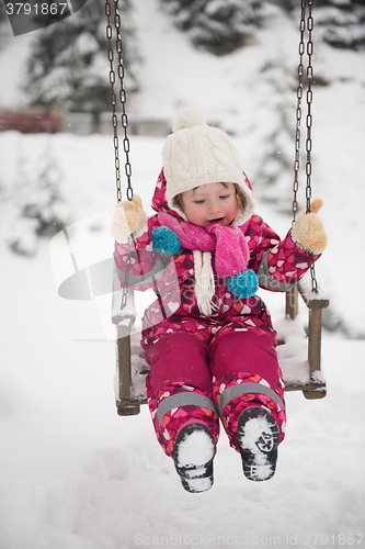 Image of little girl at snowy winter day swing in park