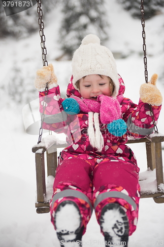 Image of little girl at snowy winter day swing in park