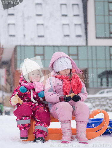 Image of portrait of two little girls sitting together on sledges