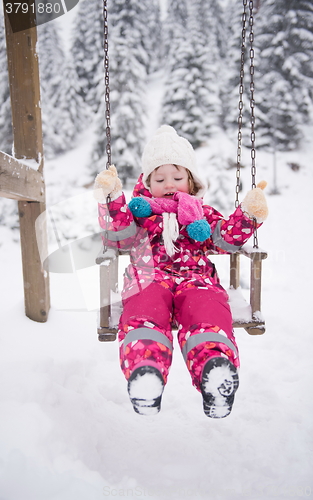 Image of little girl at snowy winter day swing in park