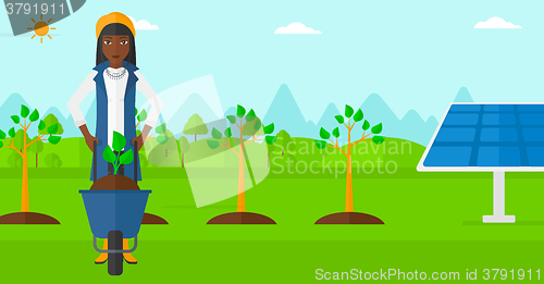 Image of Woman with plant and wheelbarrow.