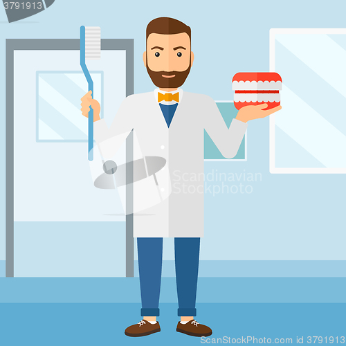 Image of Dentist with dental jaw model and toothbrush.