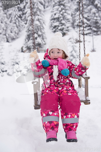 Image of little girl at snowy winter day swing in park