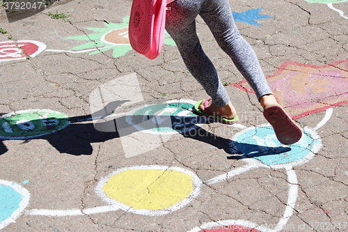 Image of girl runs on the childish drawings on the asphalt 