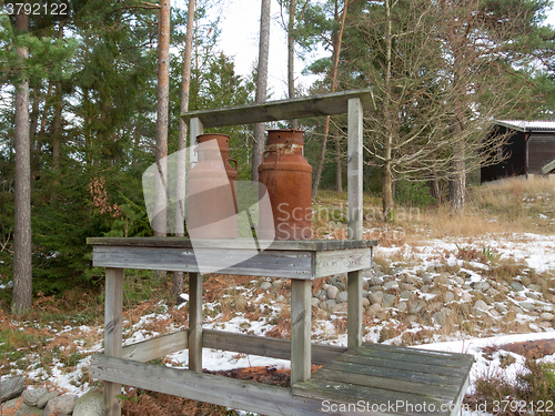 Image of two old rusty milk jug on a bench 