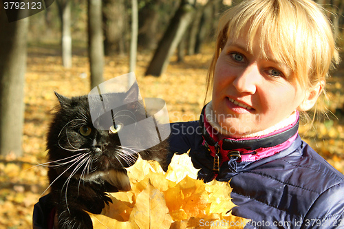 Image of pretty modern woman with black cat in the park 