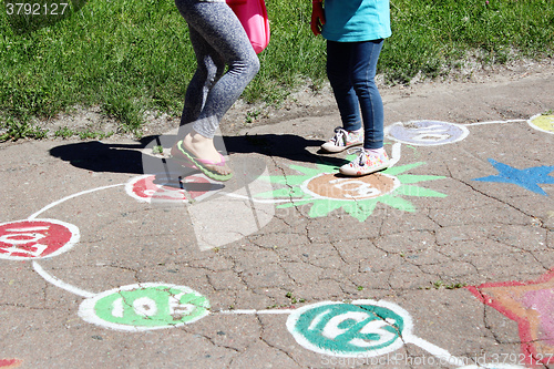 Image of girls run on the childish drawings on the asphalt 