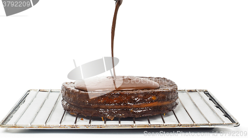 Image of Closeup of chocolate icing pouring over Sacher torte towards whi