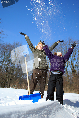 Image of mother and her daughter throw up snow on a winter background