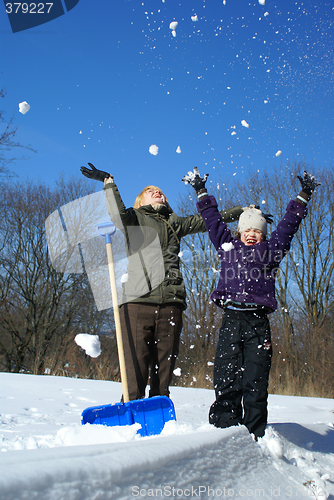 Image of mother and her daughter throw up snow on a winter background