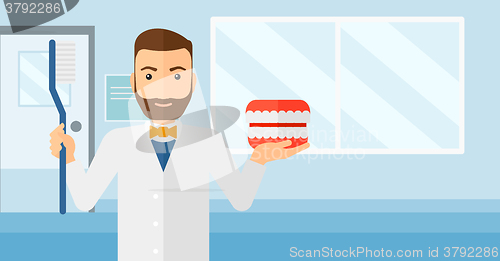 Image of Dentist with dental jaw model and toothbrush.